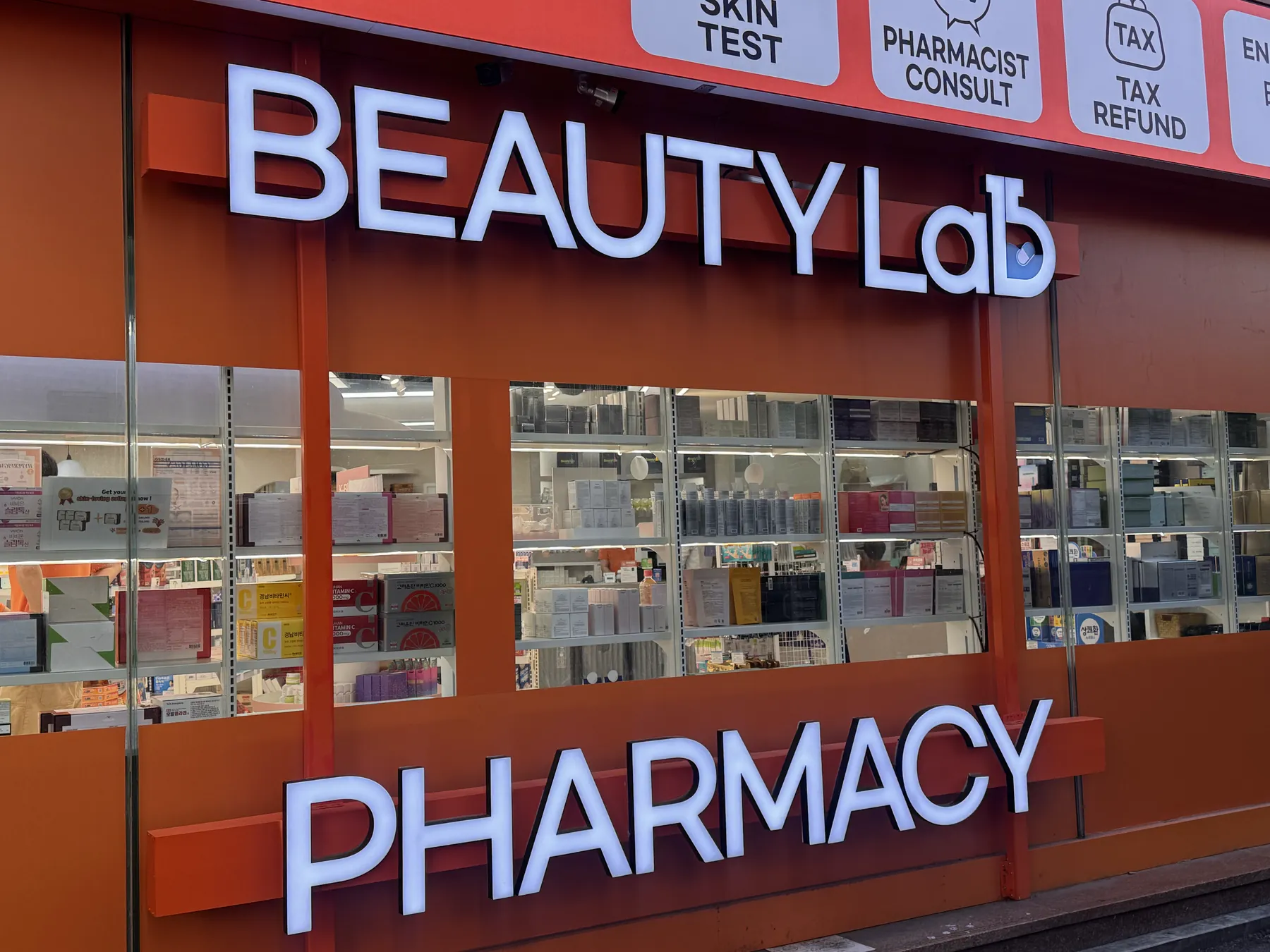 명동뷰티랩약국 외관 — 주황색 BEAUTY LAB PHARMACY 간판과 TAX REFUND 안내